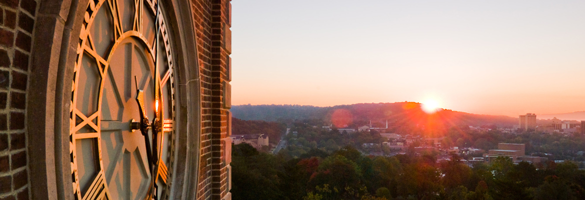 Clock of Old Main with sunrise over Fayetteville.